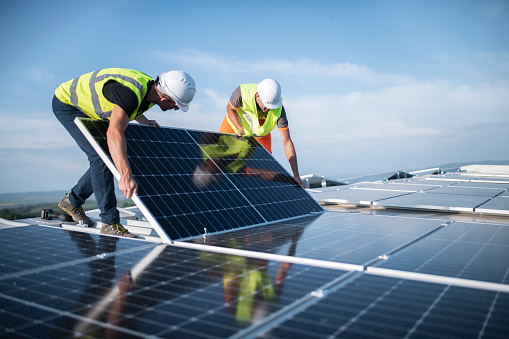 Team of Two Engineers Installing Solar Panels on the Roof in Long Island, NY