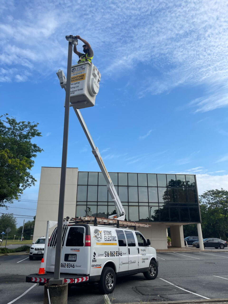 Stone Electric bucket truck performing parking lot light maintenance in a commercial setting, showcasing professional lighting services