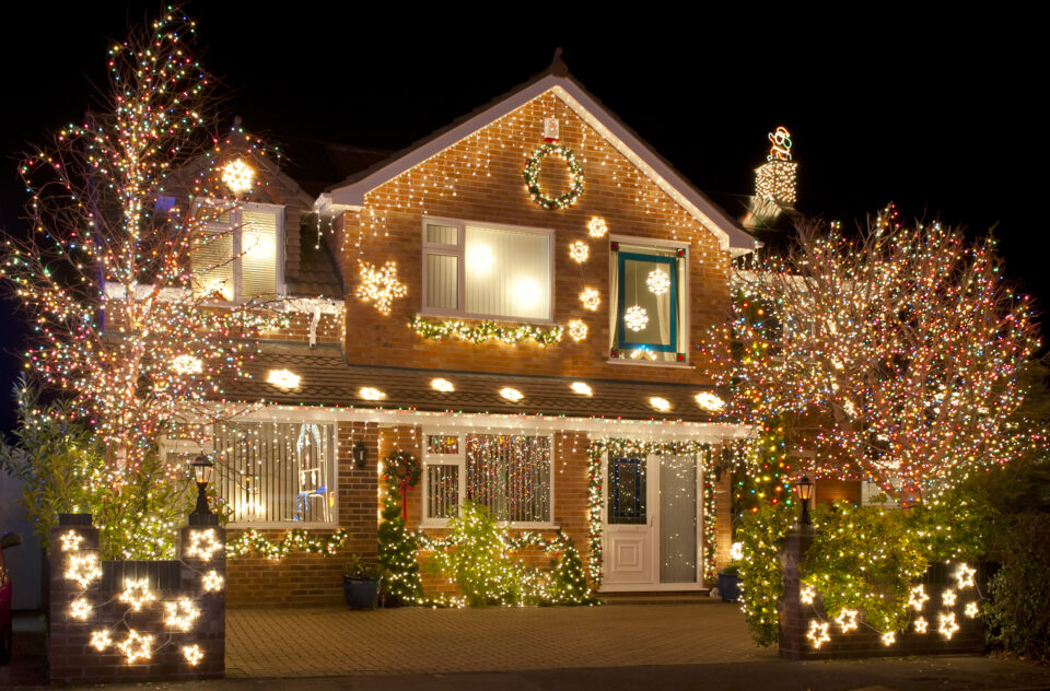 Two-story brick house illuminated with elaborate Christmas lights and decorations, showcasing professional holiday lighting installation