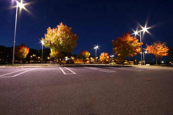 Nighttime parking lot illuminated by streetlights, with vibrant autumn trees adding warmth to the scene.