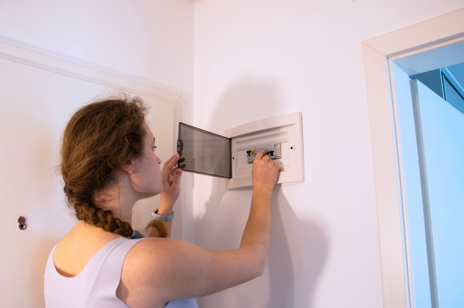 Resident resetting a home electrical breaker panel during power outage troubleshooting in Long Island, NY