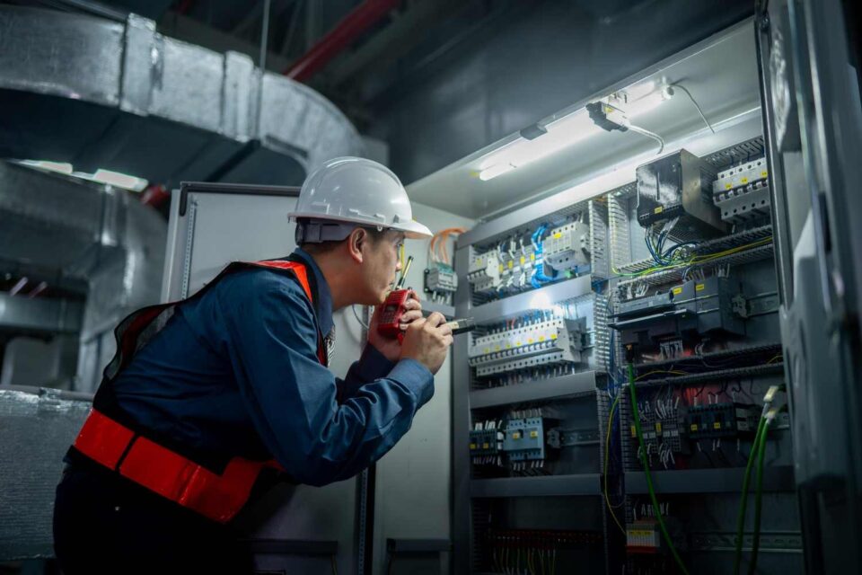 Licensed electrician inspecting industrial electrical control panel equipment in Long Island, NY